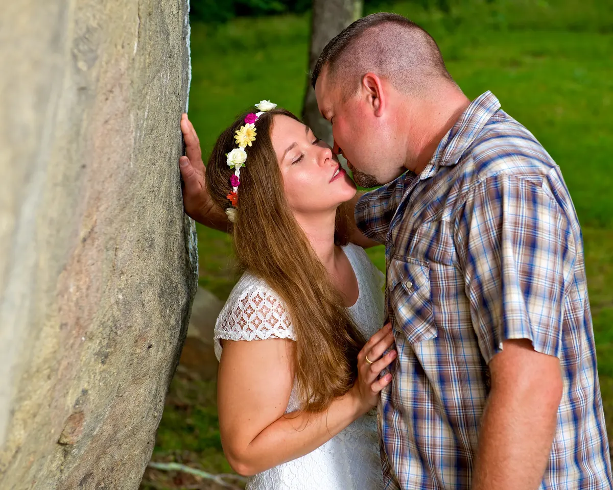 Couple kissing beside a stone wall