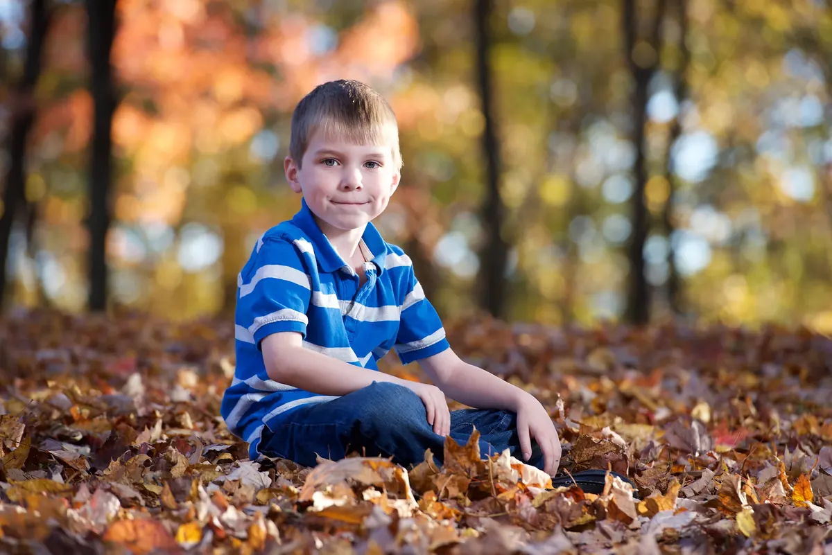 Child seated among fallen autumn leaves