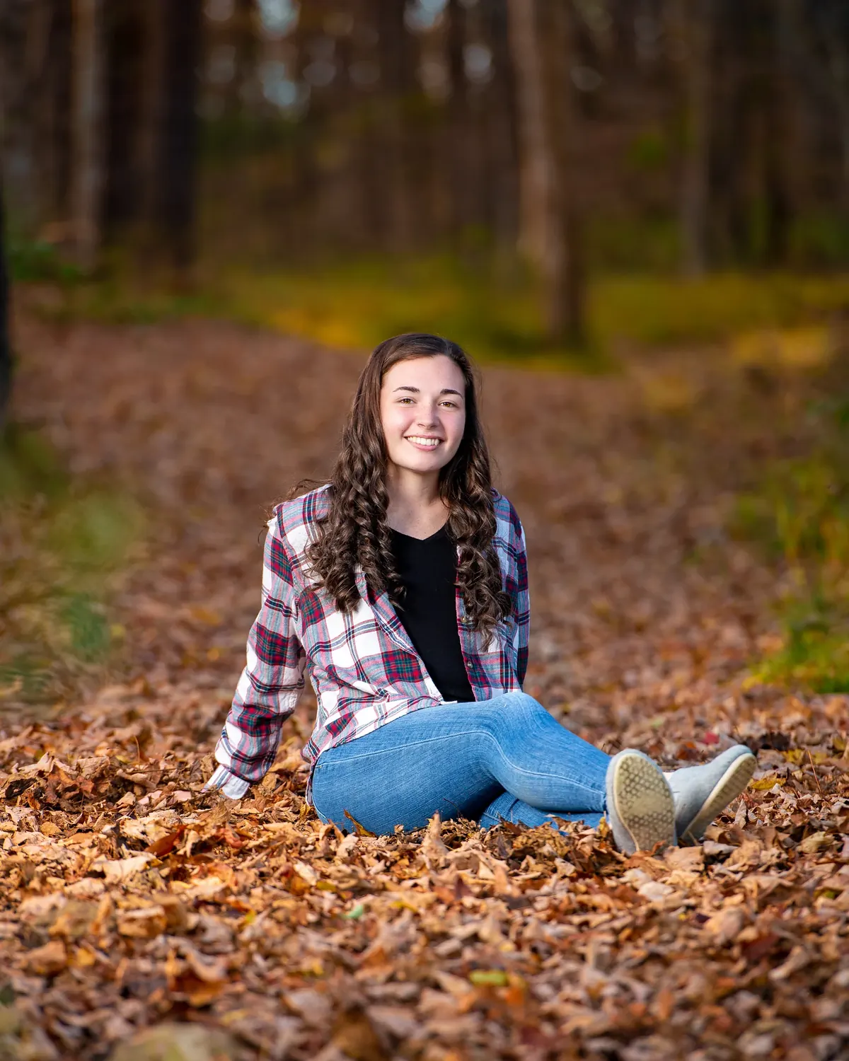Senior seated among fallen leaves in a plaid shirt